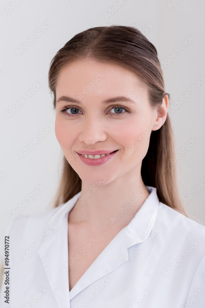 portrait of smiling cosmetologist in white coat in salon portrait of smiling cosmetologist in white coat in salon