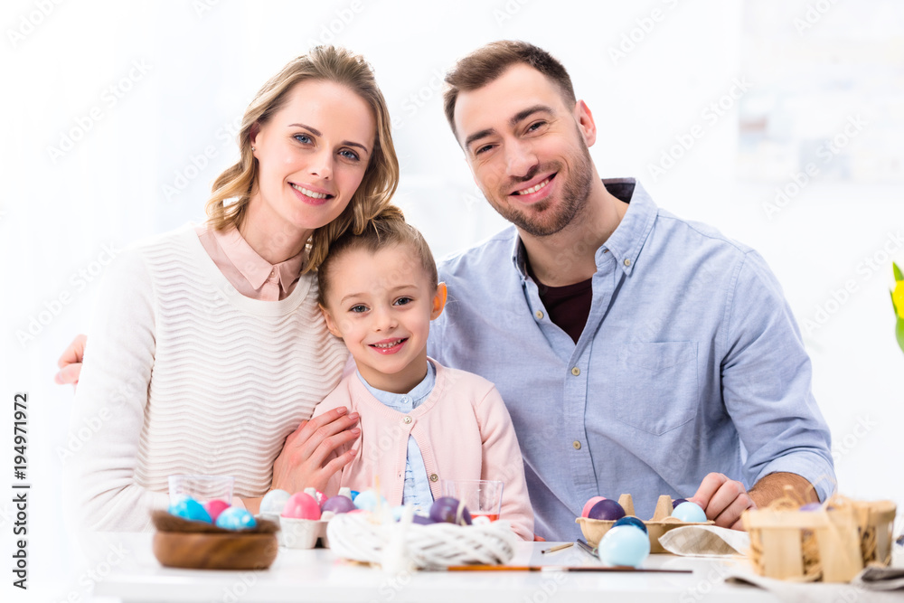 Cheerful family smiling by painted eggs for Easter