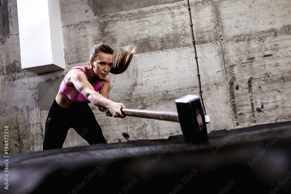 Fitness woman hitting wheel tire with hammer sledge in the gym, cross fit  training. Stock Photo | Adobe Stock