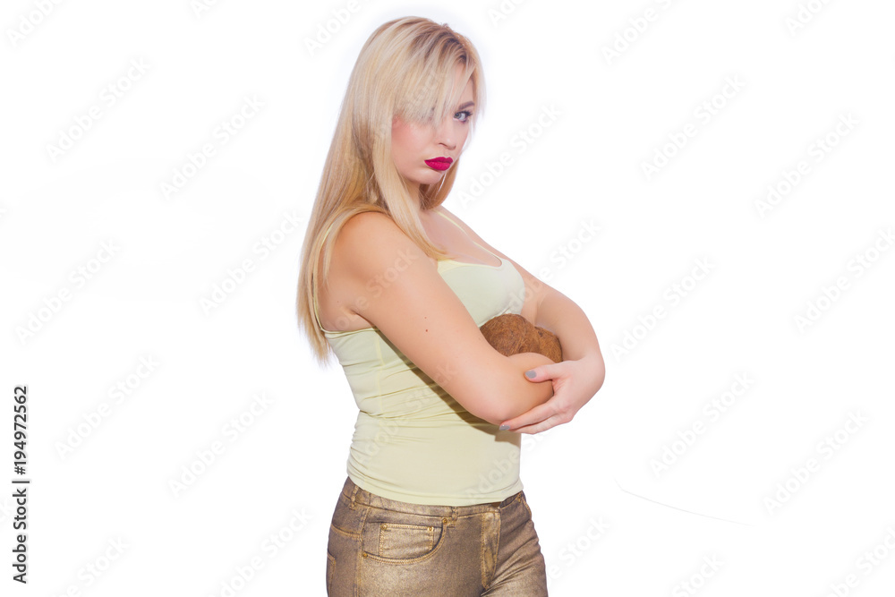 Studio portrait of a beautiful young blonde woman in a summer light yellow jersey and golden jeans. The girl is holding 2 coconuts. Concept - tropical fruits with a girl. Isolate Studio portrait of a beautiful young blonde woman in a summer light yellow jersey and golden jeans. The girl is holding 2 coconuts. Concept - tropical fruits with a girl. Isolate