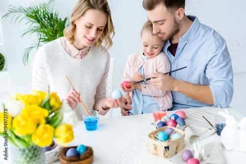 Daughter and parents painting Easter eggs
