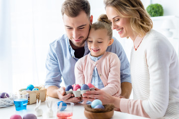 Cheerful family holding Easter painted eggs