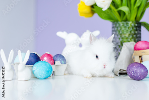 Bunny in nest on table by Easter eggs