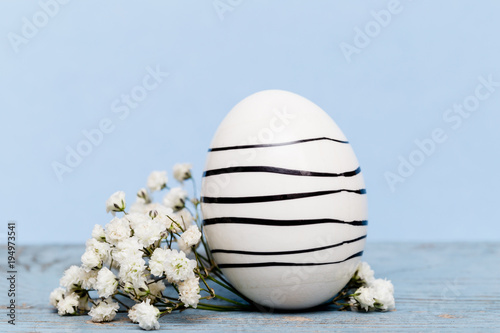 Påskägg med svarta ränder på blå bakgrund med vita blommor photo