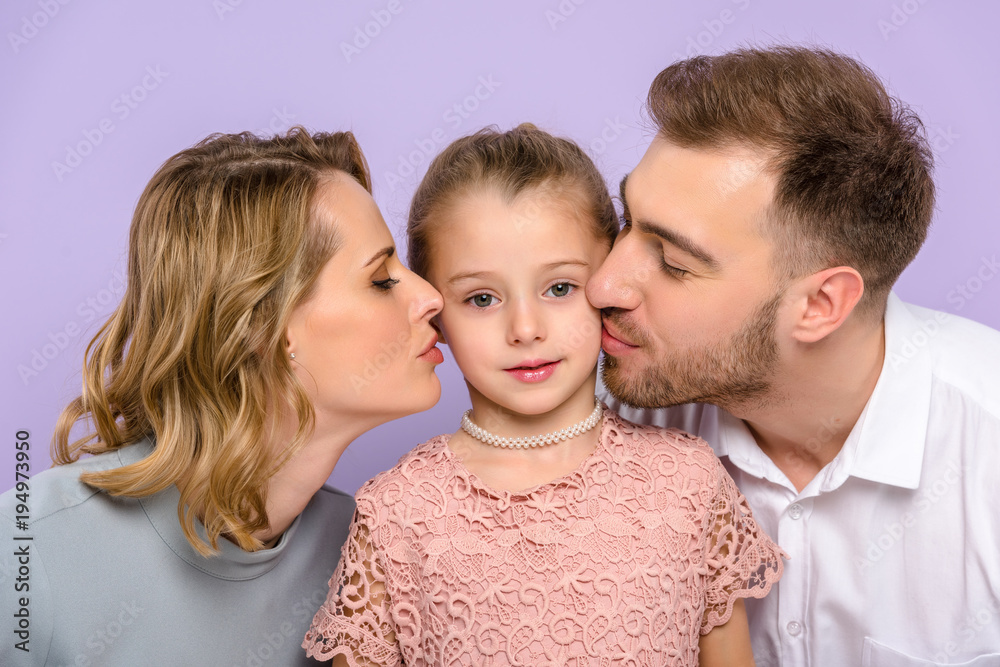 Parents kissing daughter isolated on violet Parents kissing daughter isolated on violet