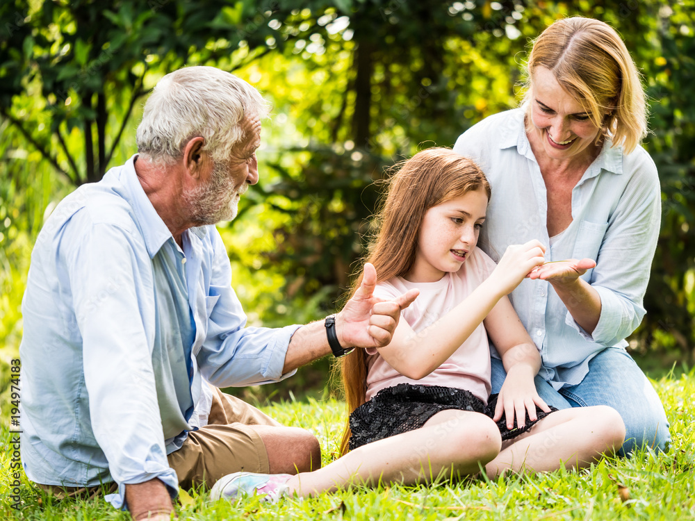 Happy family having fun together in the garden. Father, mother and daughter sitting on grass in a park. Happy family having fun together in the garden. Father, mother and daughter sitting on grass in a park.