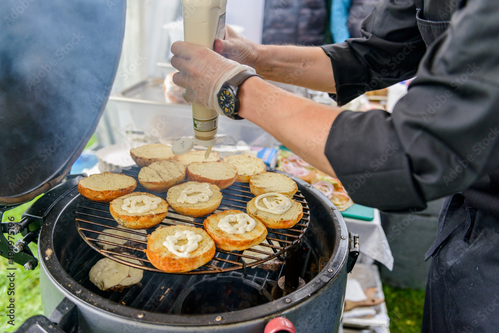 Chef making beef burgers outdoor on open kitchen international food festival event.