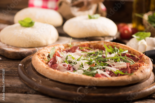 Italian Pizza with rocket salad on wooden table