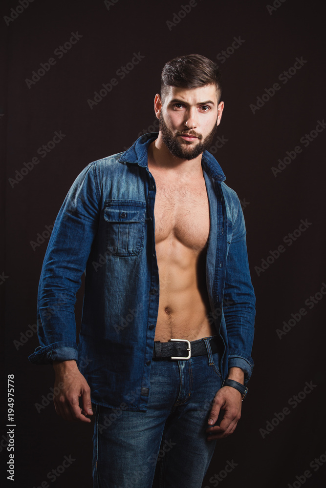 Young handsome muscular man with a beard, posing on a black background Young handsome muscular man with a beard, posing on a black background