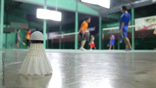 Shuttlecock laying on the floor with background of badminton practice