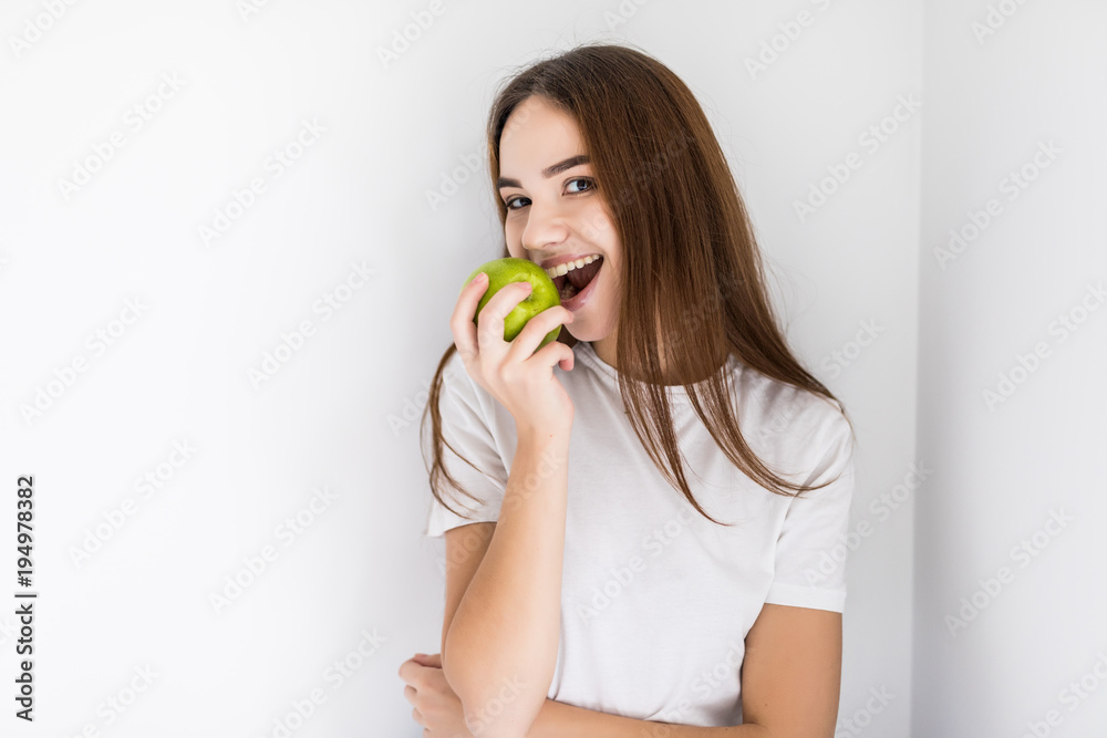 Happy young woman holding an apple and a glass of water sitting on a sofa in the living room at home Happy young woman holding an apple and a glass of water sitting on a sofa in the living room at home