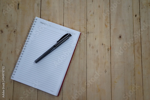 Notebook with pen on wooden table