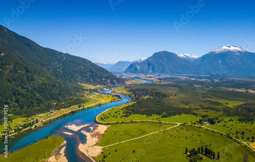 Murais de parede Aerial view of the green valley with river and mountains on the background