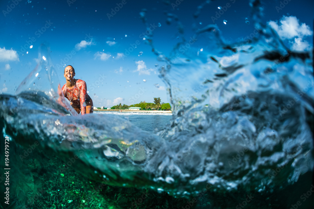 Happy surfer rides the clear ocean wave and smiles at camera. Split shot  with underwater view of the coral reef and lot of splashes Stock Photo