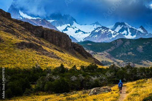 Hiker walks on the trail with mountains on the background. Patagonia, Argentina