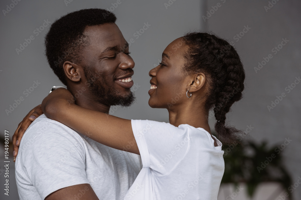 happy young african american couple hugging and smiling each other at home happy young african american couple hugging and smiling each other at home