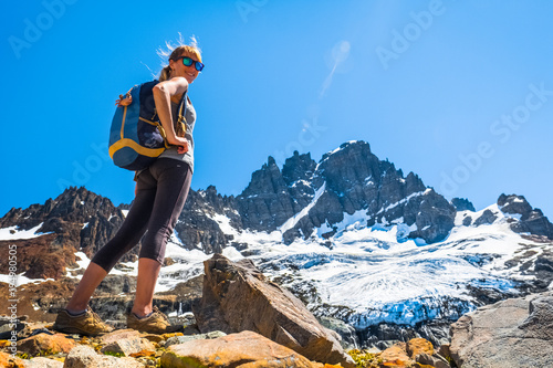 Woman hiker stands on the rocky ground with mountain and glacier on the background. Cerro Castillo mountain, Chile