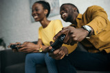happy young african american couple playing with joysticks together at home
