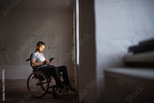 Man in wheelchair working with tablet.
