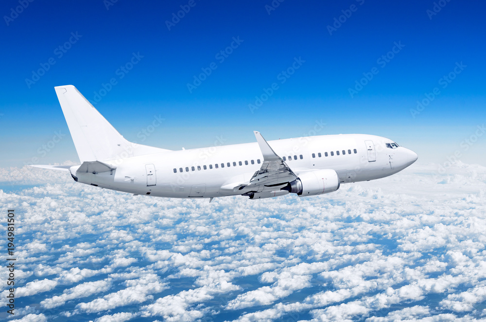 Fototapeta premium Samolot pasażerski leci wysoko nad chmurami i błękitnym niebem.