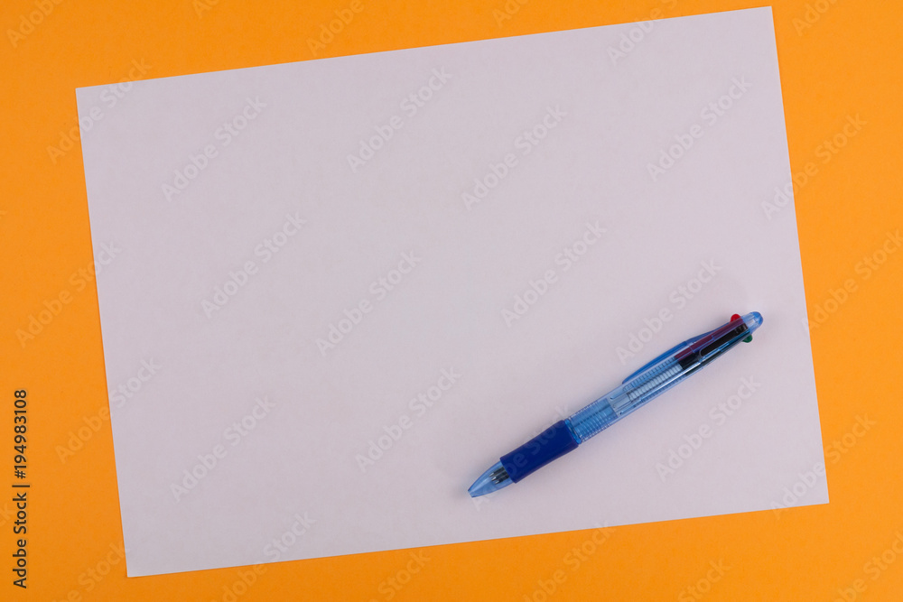 One multi color blue transparent ballpoint and white blank rectangle paper on background of orange paper with copy space One multi color blue transparent ballpoint and white blank rectangle paper on background of orange paper with copy space