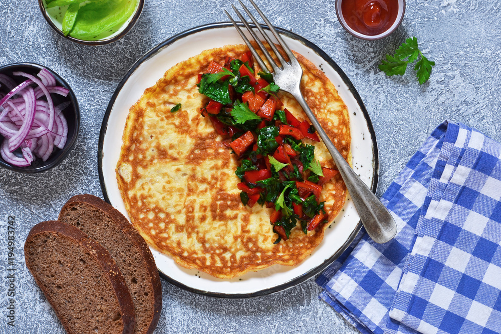 Homemade omelette with pepper and spinach for breakfast, on a gray, concrete background. Homemade omelette with pepper and spinach for breakfast, on a gray, concrete background.