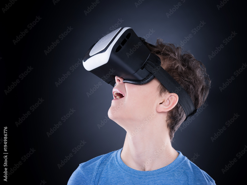 Happy teen boy wearing virtual reality goggles watching movies or playing  video games. Cheerful smiling teenager looking in VR glasses. Funny child  experiencing 3D gadget technology - close up. Stock Photo |