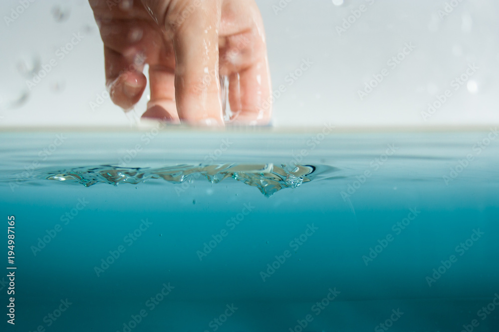 Fototapeta premium Hand greift ins Wasser zur Abkühlung oder Inspektion