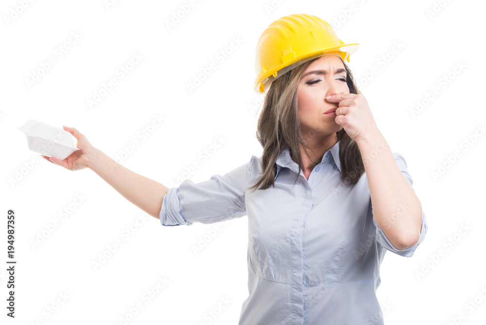 Portrait of female constructor covering nose from lunch box. Portrait of female constructor covering nose from lunch box.