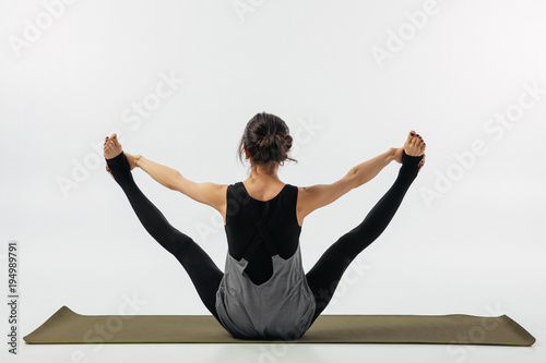 rear view of woman practicing yoga asana urdhva upavistha konasana isolated on white photo