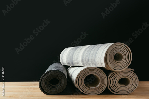 different rolled yoga mats on wooden table