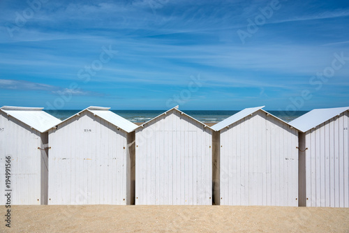 Traditional white wooden beach huts on the beach of Villers, Normandy, France © Delphotostock
