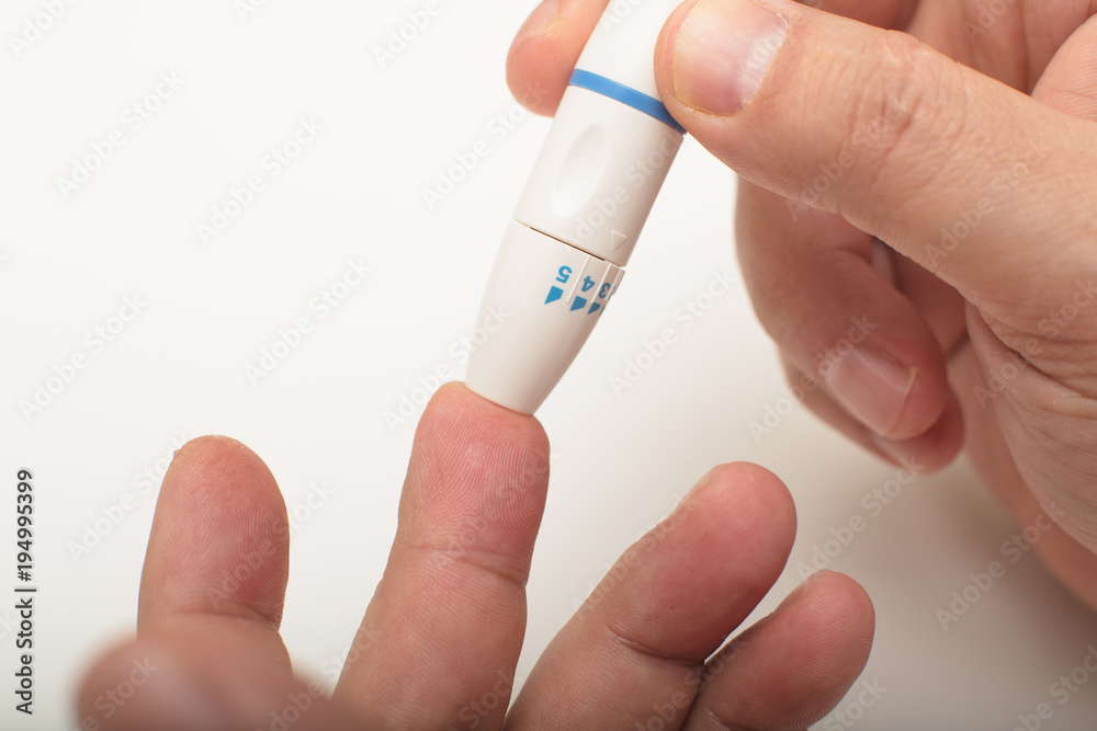 Diabetic using a lancet to take a blood sample Diabetic using a lancet to take a blood sample