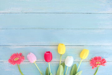 Colorful flowers bouquet on blue wooden background.  Concept flowers of spring, top view and border design,