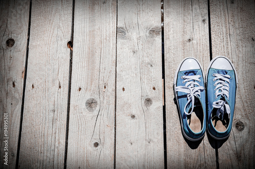 old blue gumshoes on wooden background.