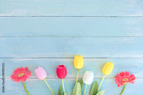Colorful flowers bouquet on blue wooden background.  Concept flowers of spring, top view and border design,