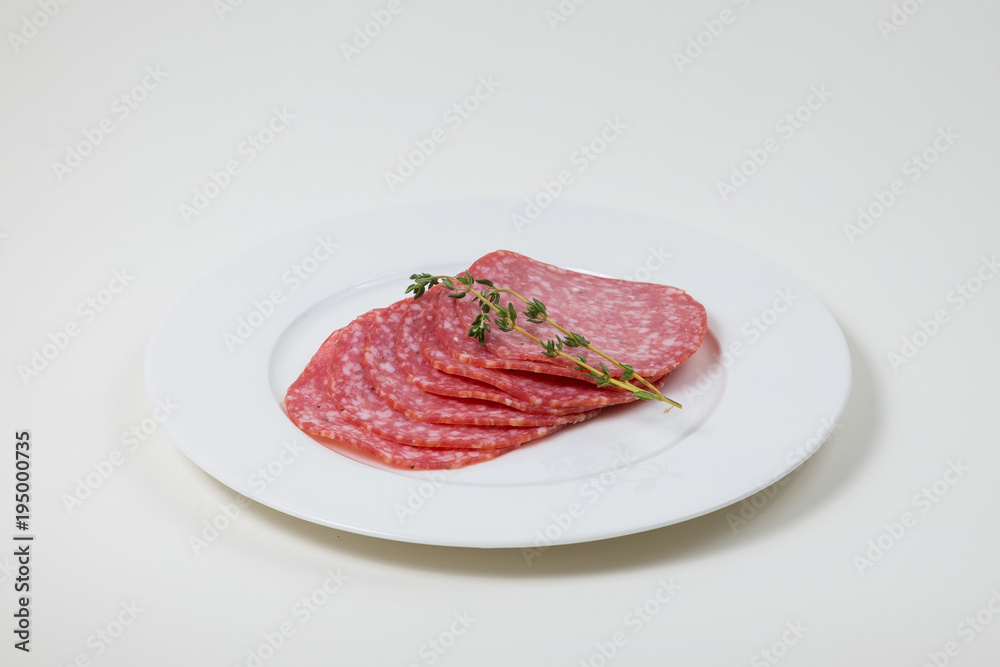Slices of Salami on a white plate on a white background isolated Slices of Salami on a white plate on a white background isolated