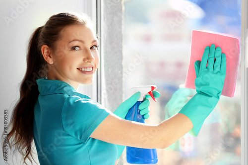 Young woman cleaning window...