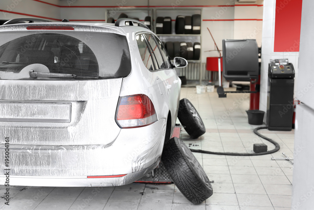 Car at tire replacement service in workshop of modern store