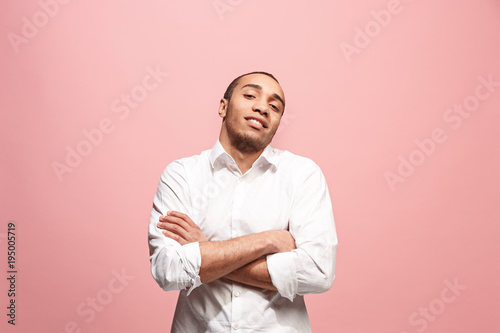 The happy business man standing and smiling against pink background.