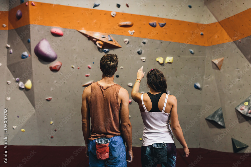 Man and woman at an indoor rock climbing gym - obrazy, fototapety, plakaty 