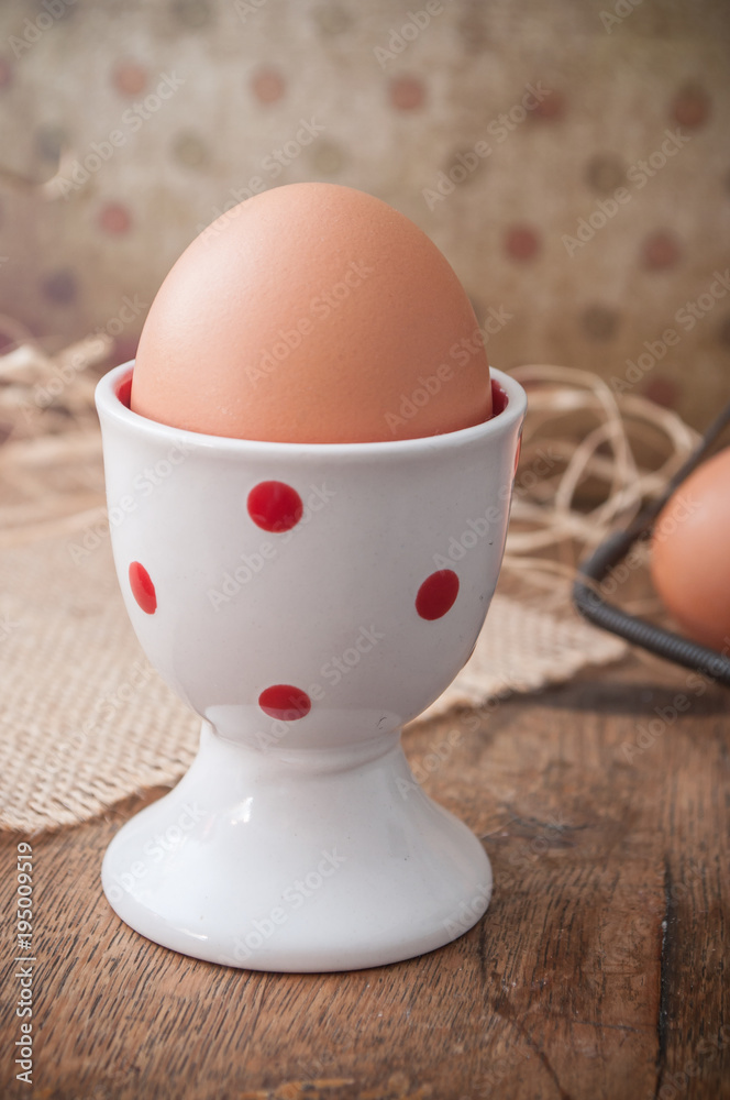closeup of eggs with eggcup and metallic basket on wooden table background closeup of eggs with eggcup and metallic basket on wooden table background