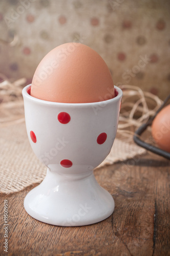 closeup of eggs with eggcup and metallic basket on wooden table background
