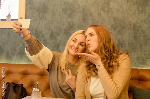 Two girls sitting in cafe and making selfie whit smart phone.