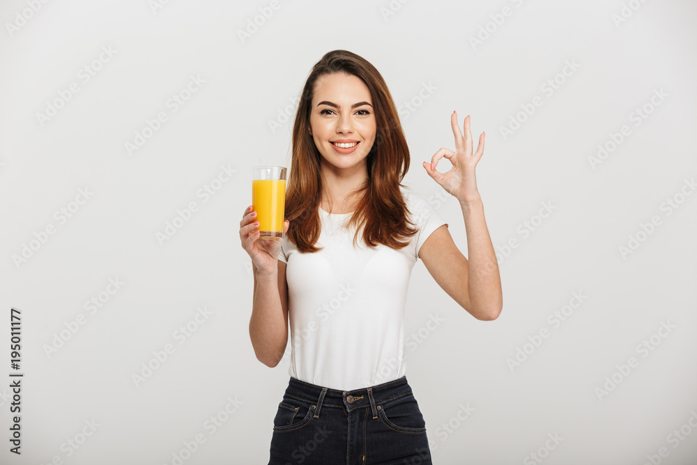 Cheerful young lady showing okay gesture holding juice. Cheerful young lady showing okay gesture holding juice.
