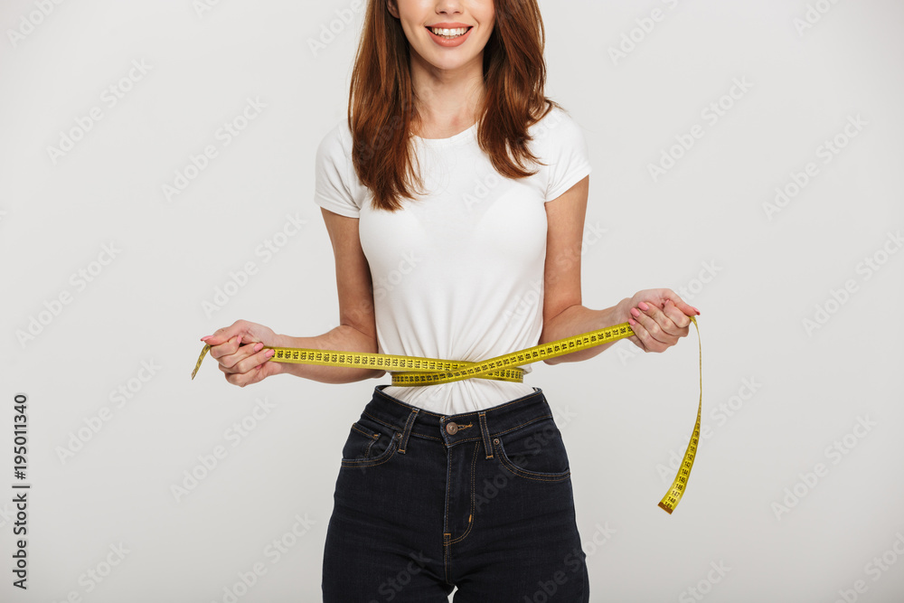 Cropped photo of cheerful young woman with centimeter around waist. Cropped photo of cheerful young woman with centimeter around waist.