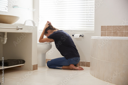 Woman Suffering With Morning Sickness In Bathroom At Home photo