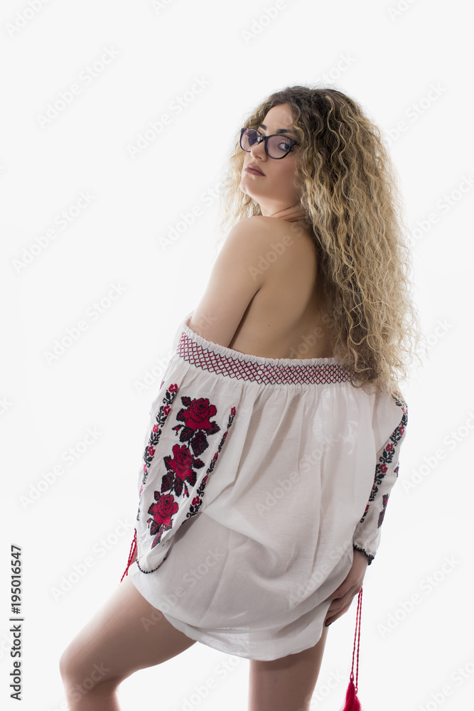 Woman with curly hair and white dress with red flowers posing on white background Woman with curly hair and white dress with red flowers posing on white background