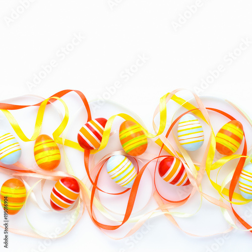 Colorful easter eggs and multicolored ribbons with empty space. Top view