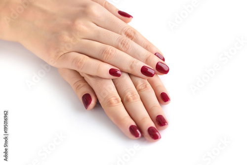 Closeup of hands of a young woman with red manicure on nails against white background